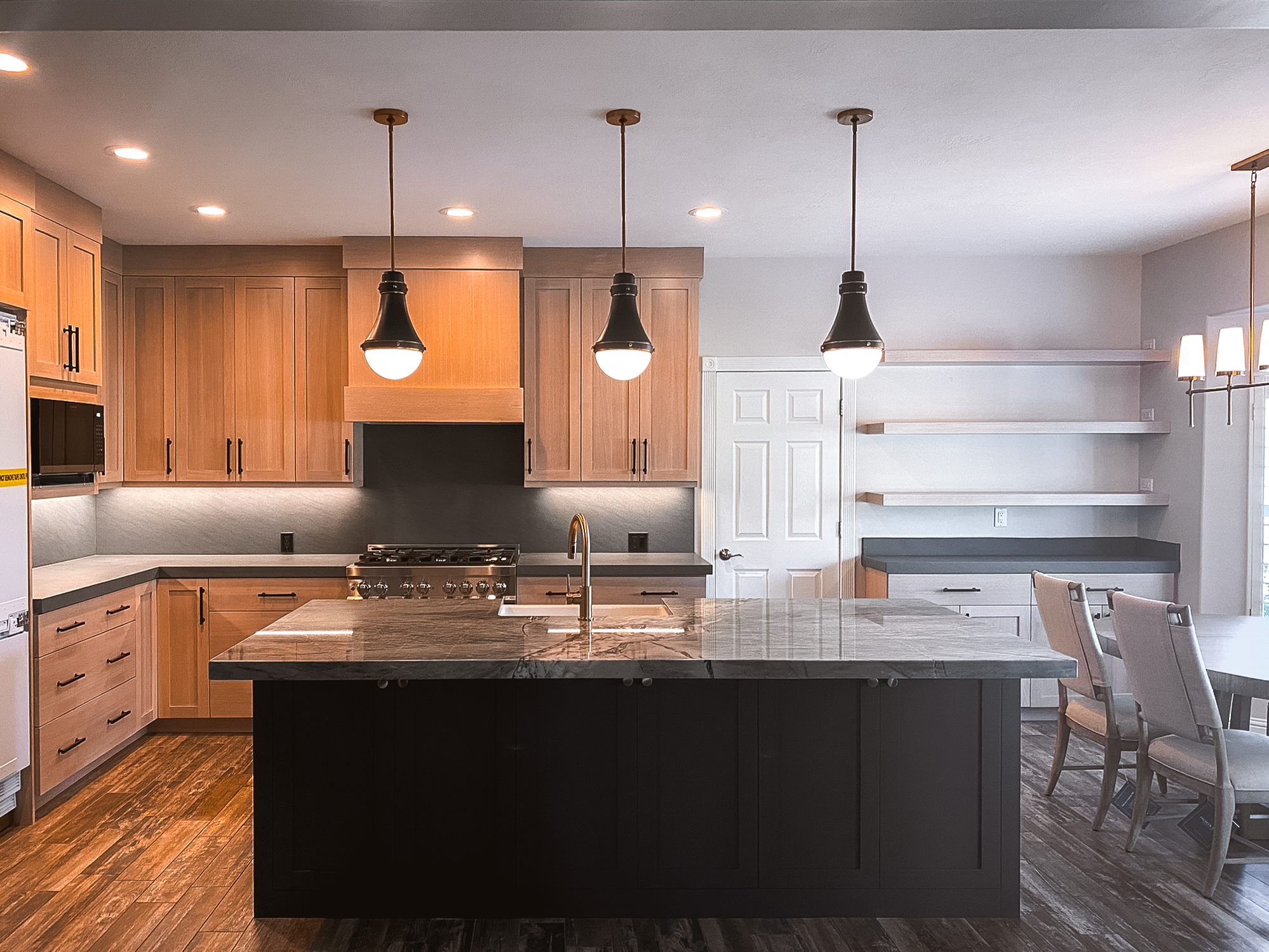 Modern kitchen with sleek cabinets, black light fixtures, granite countertops, and a black island.