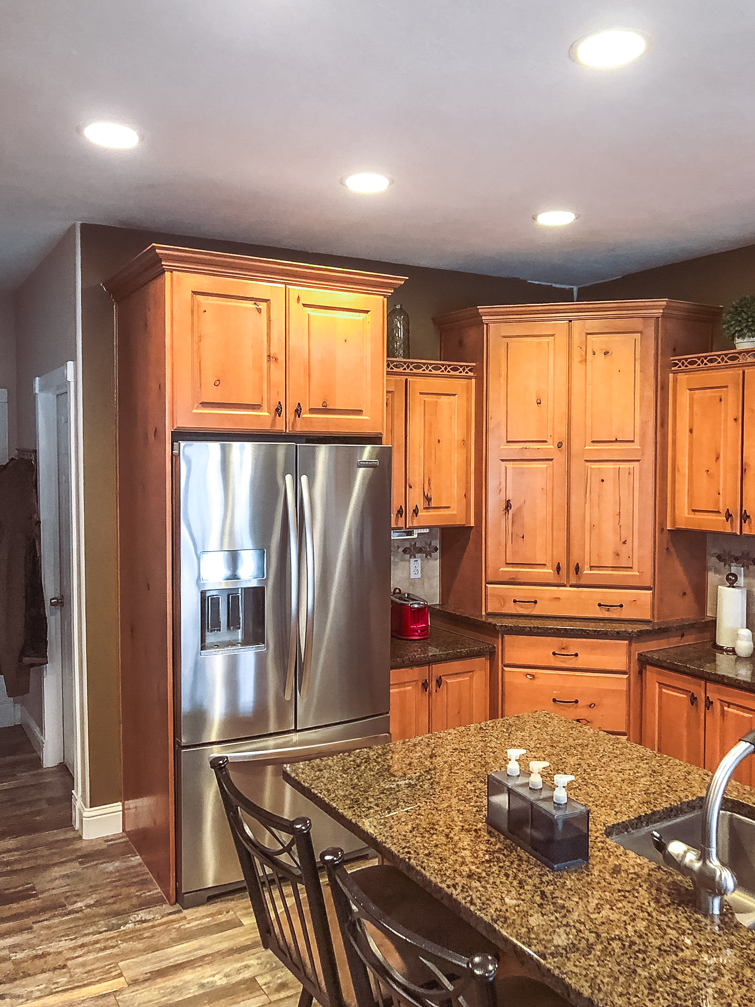 Traditional kitchen with wood cabinets, granite countertops, stainless steel fridge, and hardwood floors.
